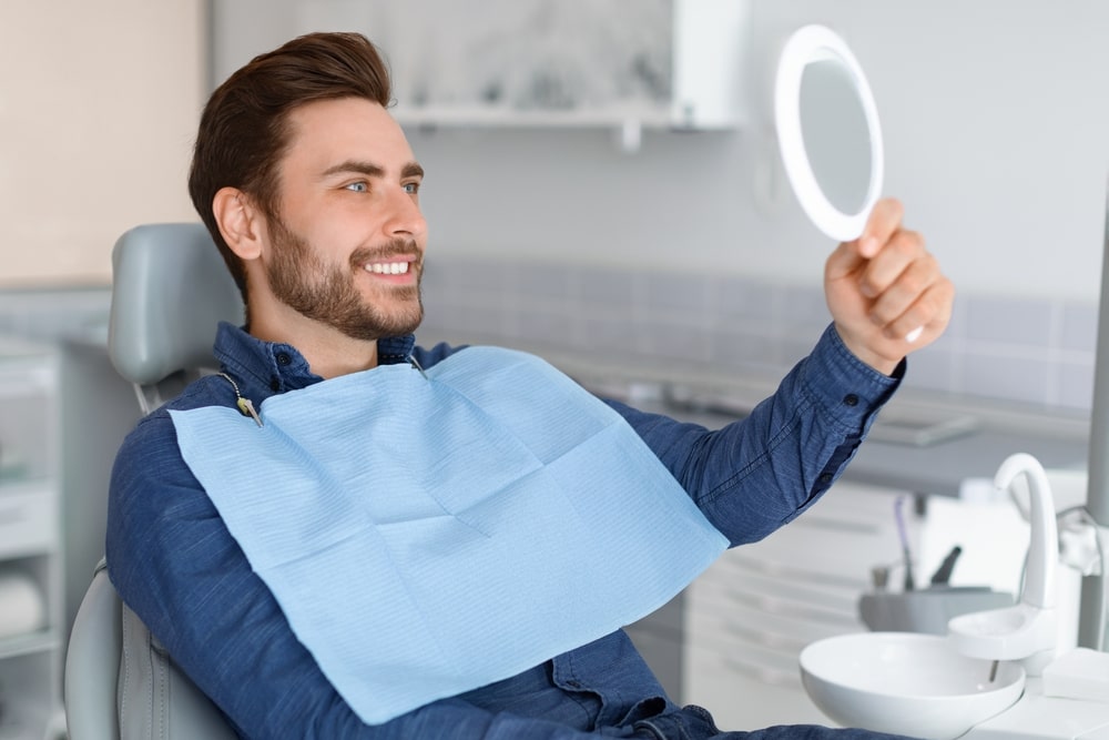 Male patient looking at his beautiful healthy white smile